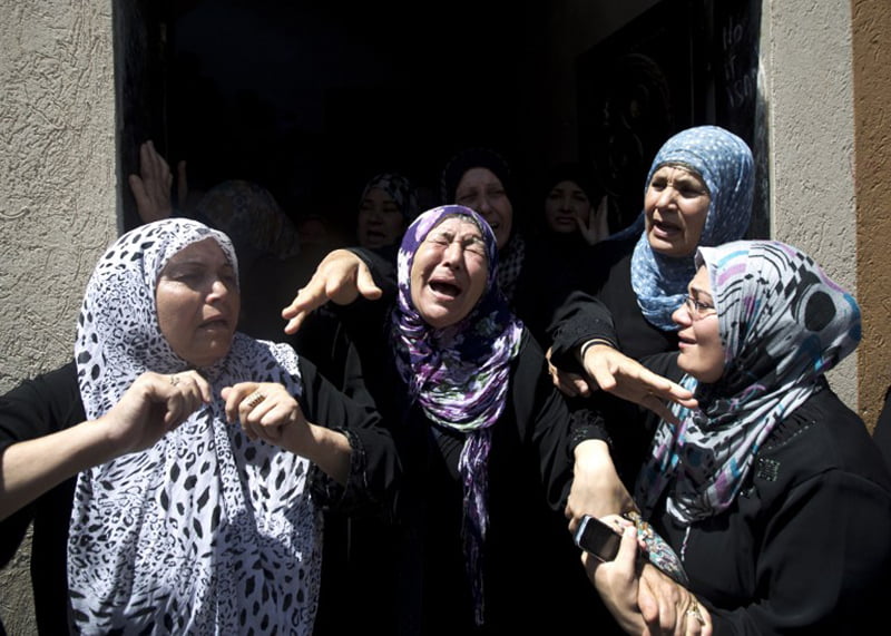 TOPSHOTS Palestinian women mourn during the funeral of Hafez Hammad, a senior Islamic Jihad commander, and five of his family members, including two women and two children, who were all killed when an Israeli missile slammed into their house in the northern Gaza Strip town of Beit Hanun on July 09, 2014. Eleven Palestinians were killed in a series of Israeli air strikes on Gaza today, hiking the overall death toll to 32 in two days, with more than 150 wounded, medics said.AFP PHOTO / MAHMUD HAMS